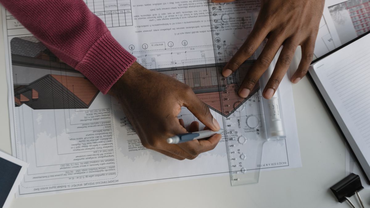 Ingénieur traçant des calculs de structure sur un plan technique de plancher